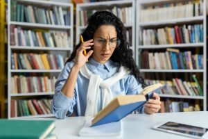 Tired overworked female student studying alone in university library, woman not understanding